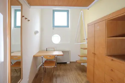 a small room with a wooden table and some windows at Hostel Celica in Ljubljana