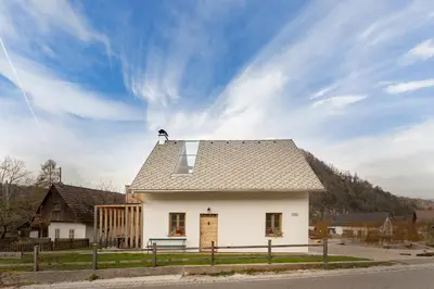 a small white house with a roof on a street at Hiša na soncu / Sun house in Zgornje Gorje