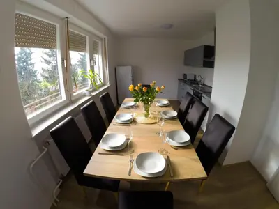 a dining room table with chairs and a vase of flowers at Apartments Andrej - Poetovio & Ptuj in Ptuj