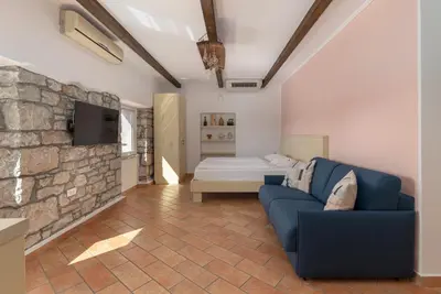 a living room with a blue couch and a stone wall at Ražman Wine Rooms in Gračišče