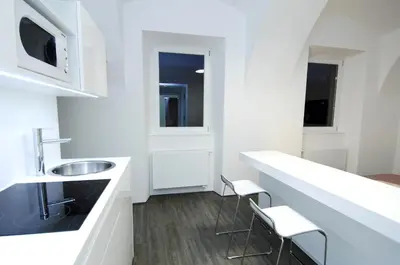 a white kitchen with a sink and two chairs at Galeria River in Ljubljana
