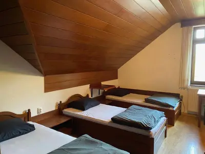 three beds in a room with a wooden ceiling at Youth Hostel Bledec in Bled