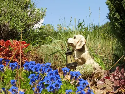 a statue of a dog in a garden with flowers at Rooms Zupančič in Bohinjska Bela
