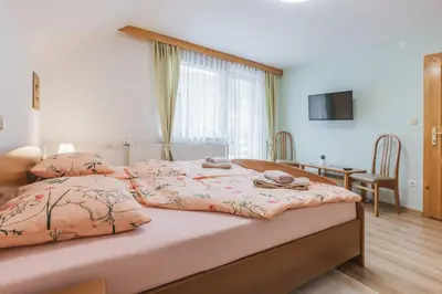 a bedroom with a bed with two pillows and a table at Rooms Zupančič in Bohinjska Bela