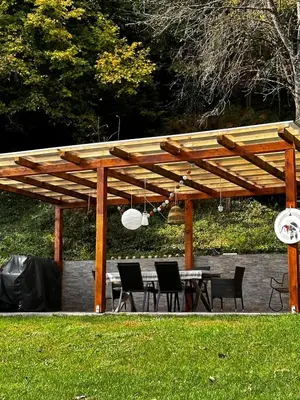 a wooden pergola with a table and chairs under it at LizMari in Podčetrtek