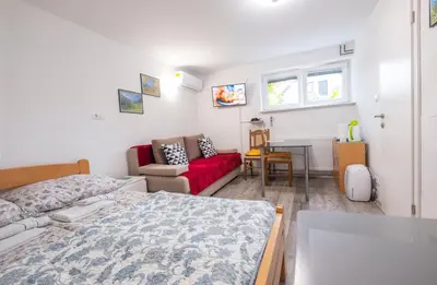 a bedroom with a bed and a living room at Studio Southwest 2 semi-basement in Ljubljana