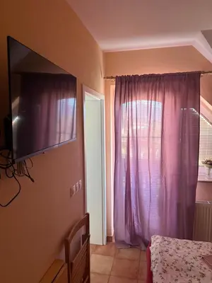 a bedroom with a window with a purple curtain at Apartments and Rooms With View on Bled in Zgornje Gorje