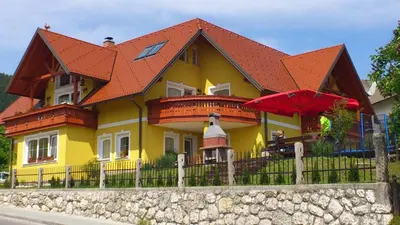 a yellow house with an orange roof and a fence at Apartments and Rooms With View on Bled in Zgornje Gorje