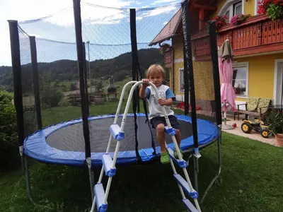 a young boy riding on a trampoline at Apartments and Rooms With View on Bled in Zgornje Gorje