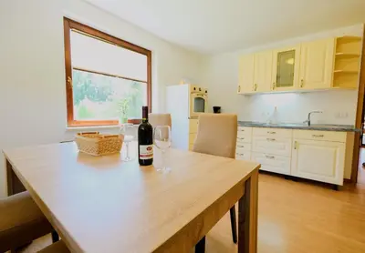 a table with a bottle of wine and two glasses at Small wooden houses and Apartments Zgornja Dobrava in Radovljica