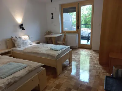 a bedroom with two beds and a table and a window at Sobe Levc in Mozirje