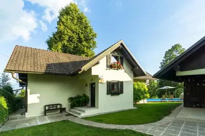 a small white house with a bench in the yard at Holiday House in Nature with Pool, Pr Matažič in Kamnik
