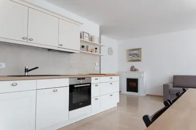 a kitchen with white cabinets and a table and a fireplace at Auredius Deluxe Apartment in Kranjska Gora