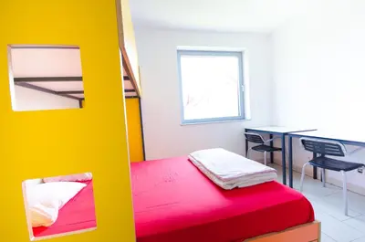 a bedroom with a red bed and a desk at Simbol Rooms with free private parking in Ljubljana