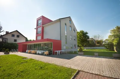 a red and white building with tables in front of it at Simbol Rooms with free private parking in Ljubljana