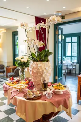 a table with a vase filled with flowers and food at Boutique Hotel Dobra Vila Bovec in Bovec