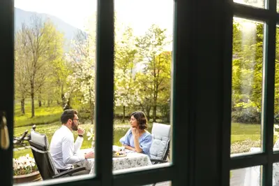 a man and woman sitting at a table looking out a window at Boutique Hotel Dobra Vila Bovec in Bovec