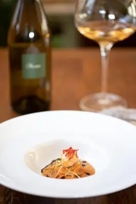 a white plate with a piece of food and a glass of wine at KABAJ Wine & Dine in Dobrovo
