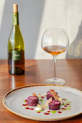 a plate of food and a glass of wine on a table at KABAJ Wine & Dine in Dobrovo