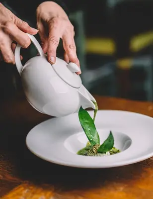 a person pouring a tea pot on a plate at KABAJ Wine & Dine in Dobrovo