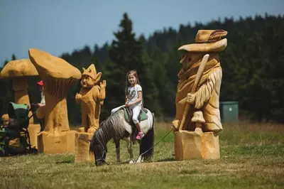a little girl riding on a toy horse at Rogla Apartma Kekec in Zreče