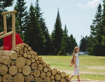 a little girl walking next to a pile of logs at Rogla Apartma Kekec in Zreče