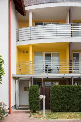 a yellow building with a balcony with two chairs on it at Apartments Moravske Toplice in Moravske Toplice