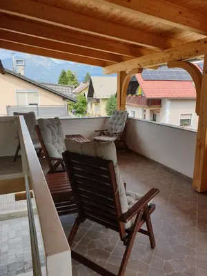a balcony with chairs and a wooden pergola at Dežman Apartments & Rooms in Kranj