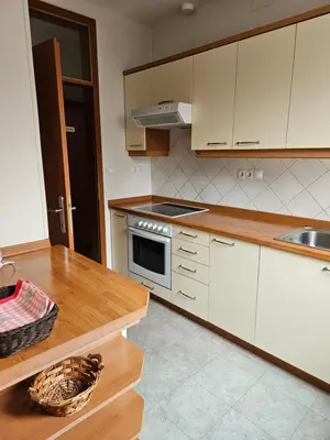 a kitchen with white cabinets and a wooden counter top at Dežman Apartments & Rooms in Kranj