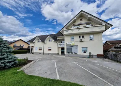 a large white building with a parking lot at Dežman Apartments & Rooms in Kranj