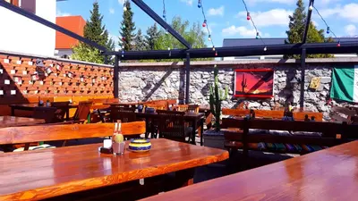 a restaurant with wooden tables and chairs and a stone wall at Resort Vidmar - Apartments Vidmar near Bled in Lesce