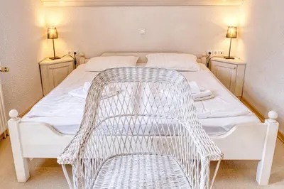 a white bed with a wicker chair in a room at Pr Bevc in Bled