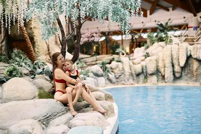 a woman and a baby sitting on rocks next to a swimming pool at Hotel Terme - Terme Čatež in Čatež ob Savi