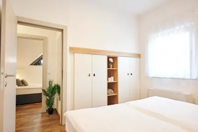a bedroom with a white bed and a mirror at Apartments Čatež - Terme Čatež in Čatež ob Savi