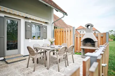 a patio with a table and chairs and a pizza oven at Apartments Čatež - Terme Čatež in Čatež ob Savi