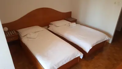 two beds in a small room with white sheets at Marinčič Inn in Škocjan