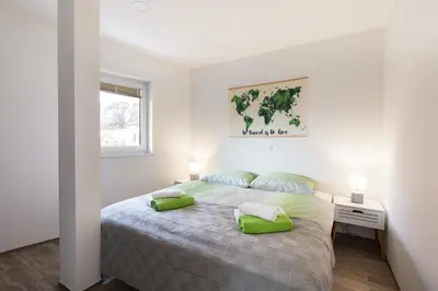 a white bedroom with a large bed with green pillows at Felix apartment Tour As Ljubljana in Ljubljana