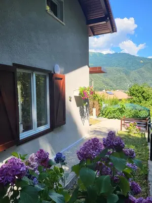 a house with purple flowers in front of a window at Cosy cottage with views near Kobarid in Kobarid