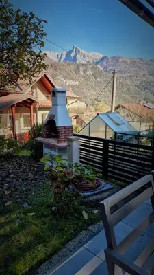 a house with a fireplace in a yard with a mountain at Cosy cottage with views near Kobarid in Kobarid