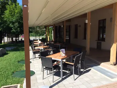 an outdoor patio with wooden tables and chairs at Hotel Marinšek in Naklo