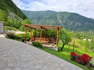a wooden bench in a gazebo with mountains in the background at APARTMA ANA IDA in Srpenica