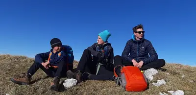three people sitting on a hill with their luggage at Apartments Tourist Farm Štorman with EV Ch-Station in Tržič