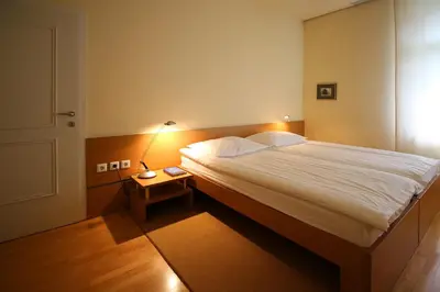 a bedroom with a large bed and a night stand at Apartments Villa Boltez in Kranj