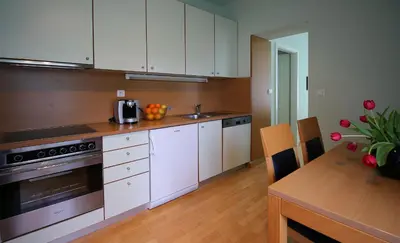 a kitchen with white cabinets and a wooden table at Apartments Villa Boltez in Kranj