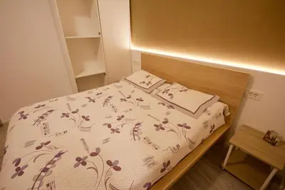 a small bedroom with a bed with a wooden headboard at Albina apartment in Ljubljana