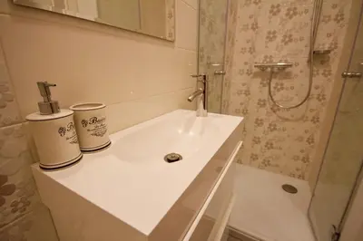 a white bathroom with a sink and a shower at Albina apartment in Ljubljana