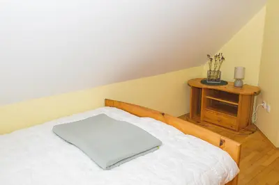 a bedroom with a white bed and a wooden table at Apartma Smučka pod Roglo in Zreče