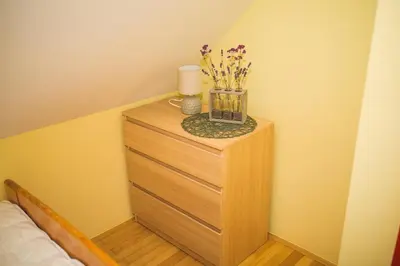 a wooden dresser with a vase of flowers on it at Apartma Smučka pod Roglo in Zreče