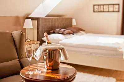 a hotel room with a bed and a table with wine glasses at B&B Dvor Tacen in Ljubljana