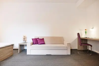 a living room with a white couch with a purple pillow at Hotel Meksiko in Ljubljana
